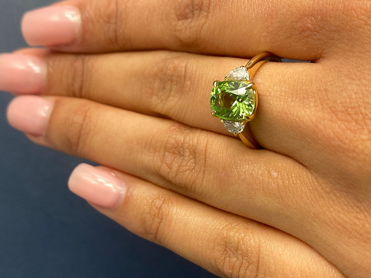 14K yellow gold ring features an oval-shaped peridot with two half-moon diamonds on each side
