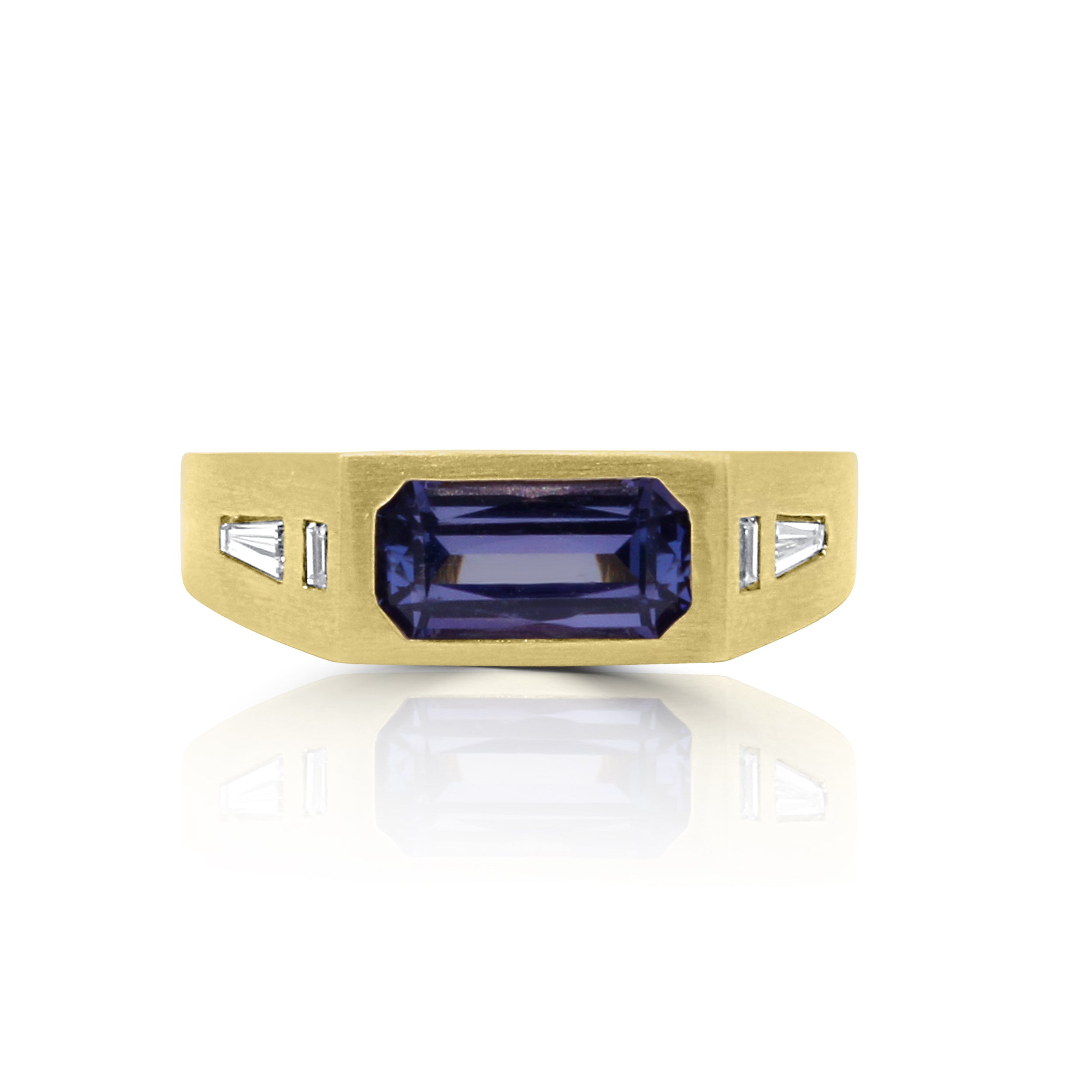 andmade yellow gold ring featuring a vibrant emerald-cut tanzanite gem with baguette diamonds on the sides and a matte satin finish
