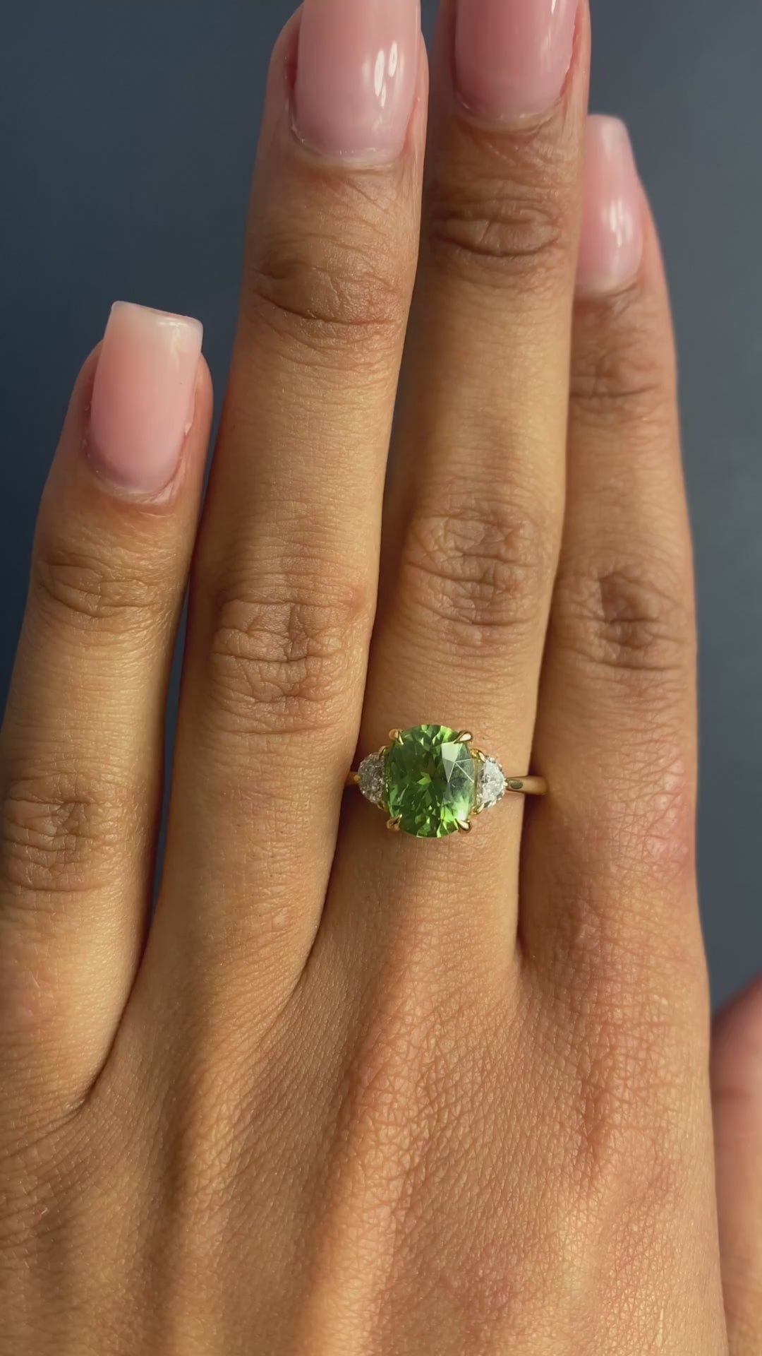 14K yellow gold ring features an oval-shaped peridot with two half-moon diamonds on each side